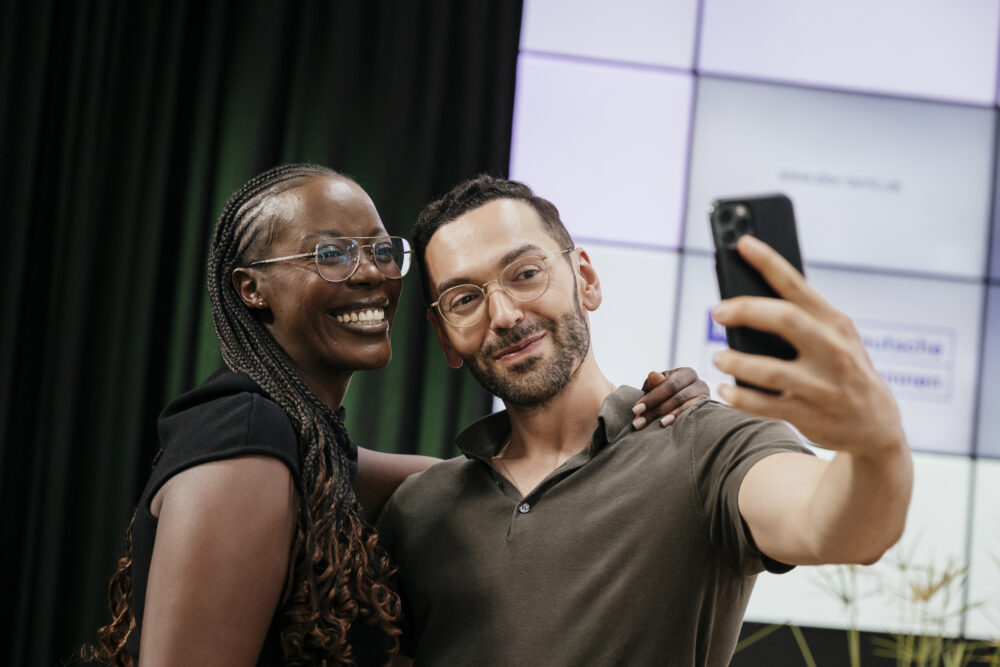 Der Speaker Atahan Demirel macht ein Selfie mit der Moderatorin Anna Dushime.
