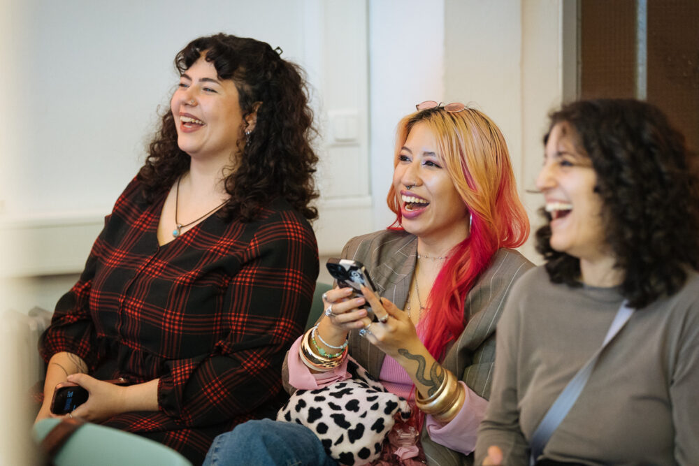 Das Bild zeigt drei lachende Frauen auf einer Veranstaltung des Mentoring@NRW.