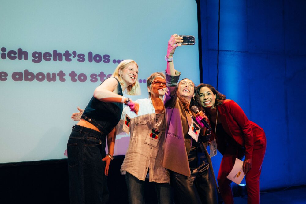 Das Foto zeigt vier Personen, die auf einer Veranstaltung ein Selfie machen.
