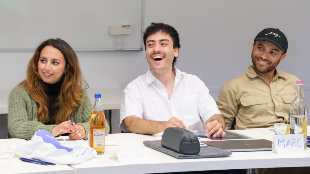 Drei Mentees sitzen am Tisch und lachen