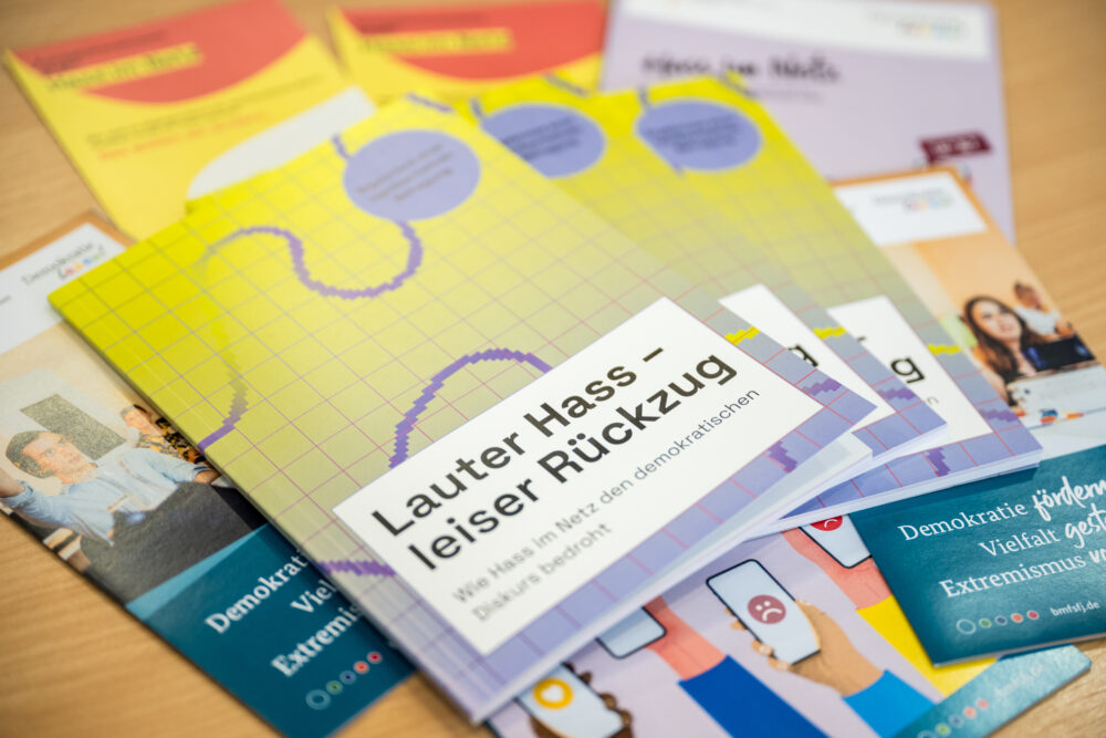 Das Foto zeigt die Broschüre der Studie Lauter Hass – leiser Rückzug auf einem Tisch. Darunter liegen mehrere andere Broschüren