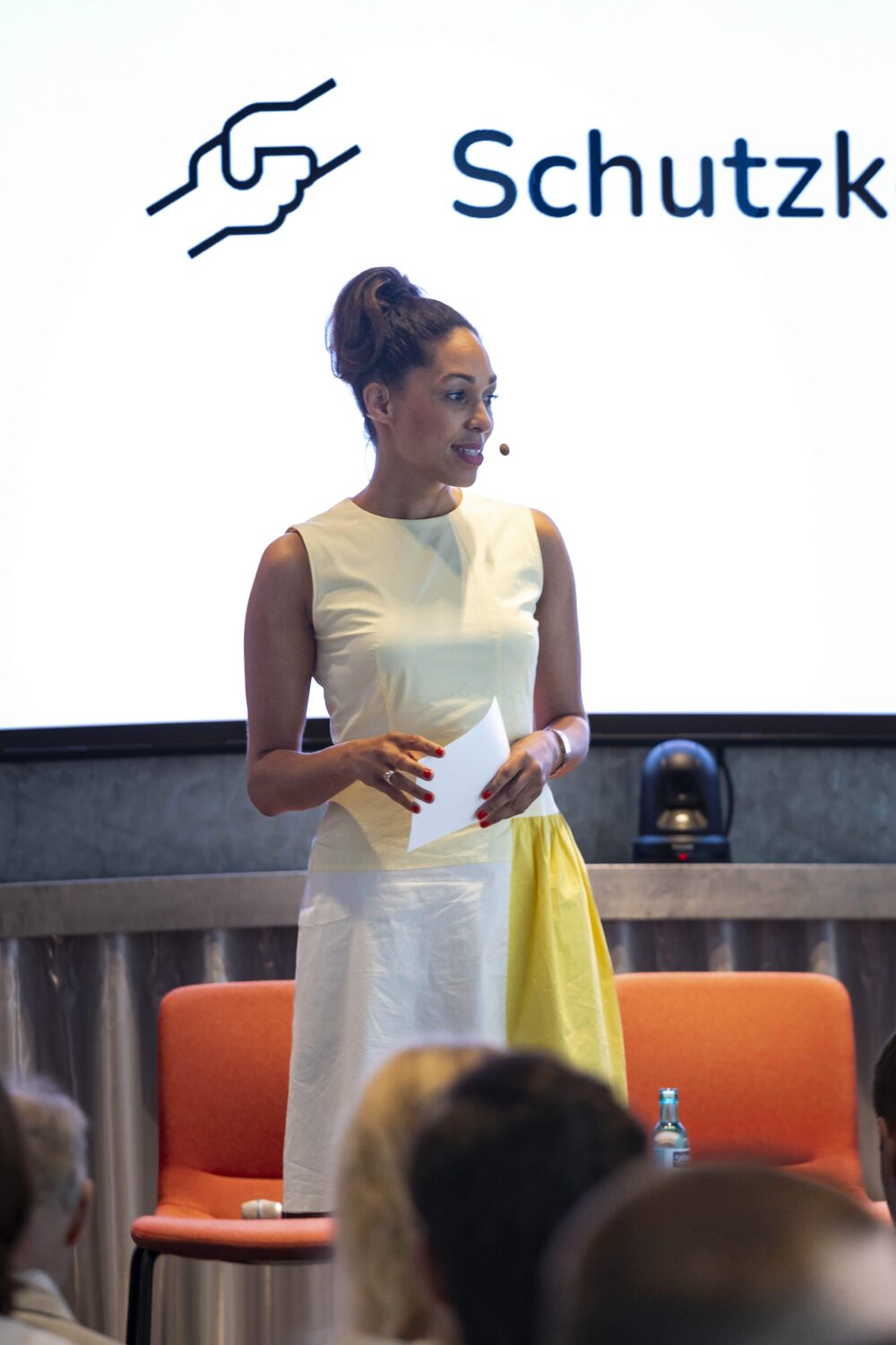 Das Bild zeigt eine Frau, die auf einer Veranstaltung vom Schutzkodex moderiert.