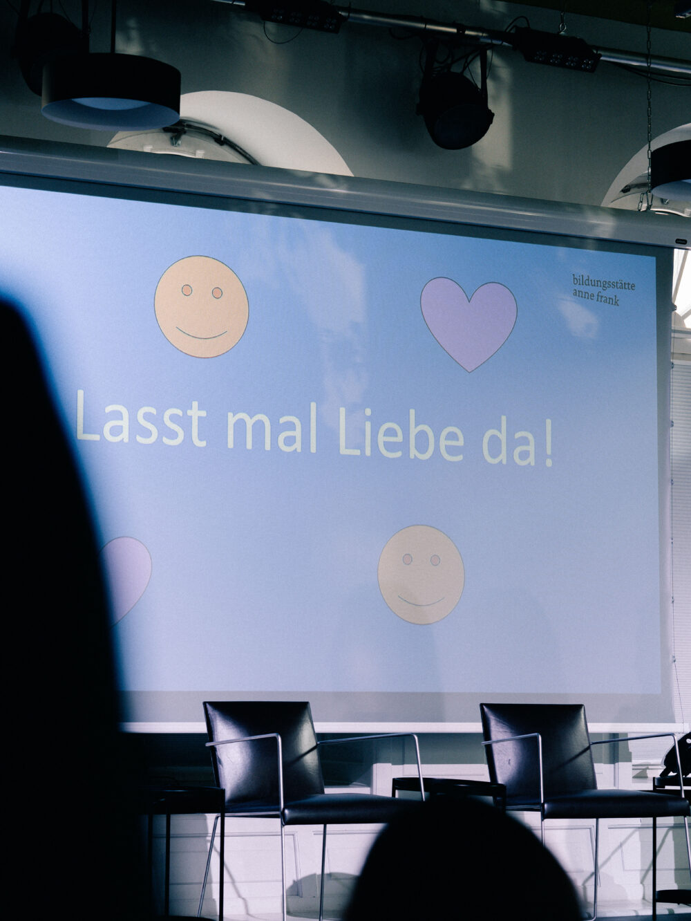 Leinwand mit den Symbolen eines Smiley-Gesichts und eines Herzens sowie dem Text 'Lasst mal Liebe da!'
