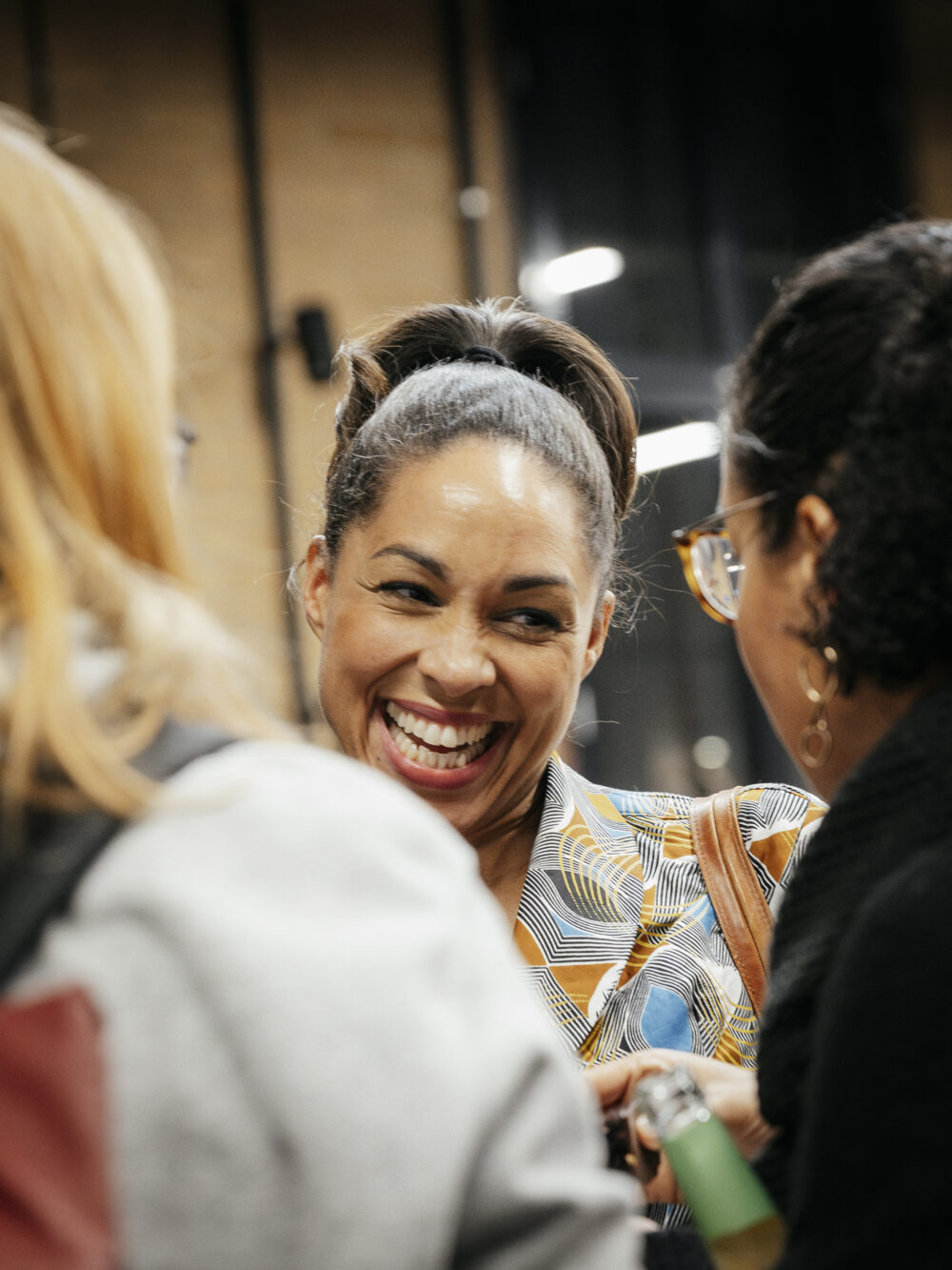 Das Bild zeigt drei NxM-Teilnehmer*innen lachend im Gespräch.