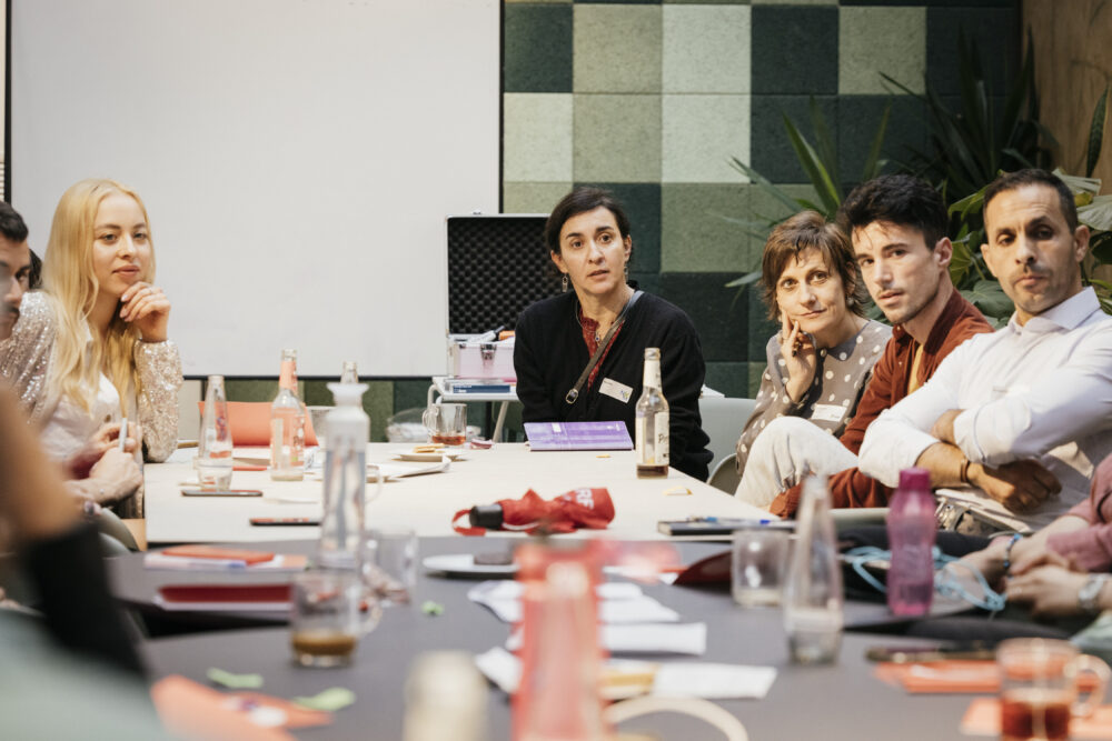 Das Foto zeigt mehrere Personen, die in einer Workshopsituation um einen Tisch sitzen.
